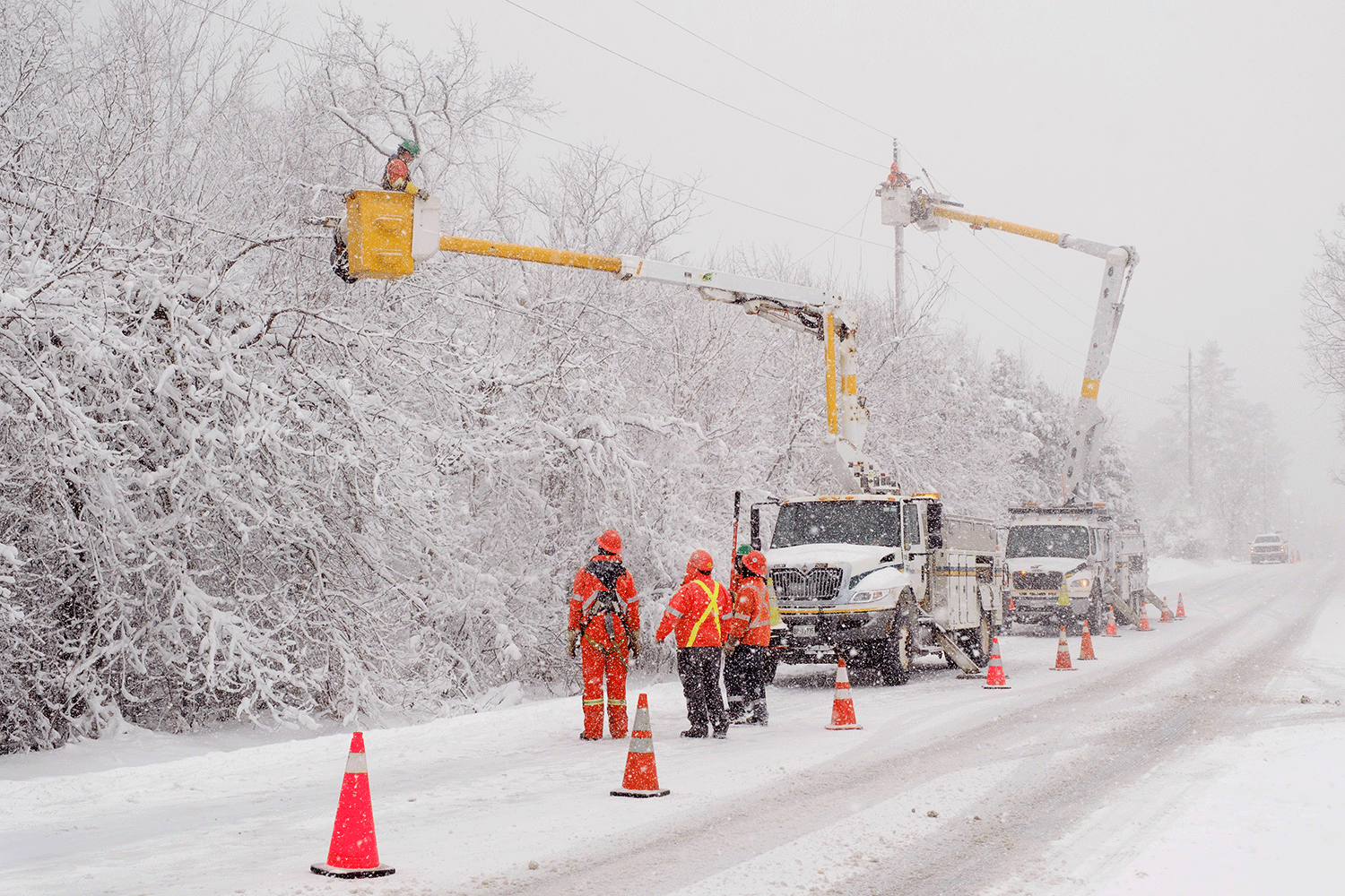 Hydro crews working in bucket trucks along a snowy road