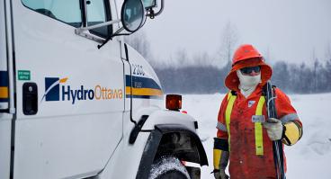 Hydro Ottawa crew member walking toward Hydro Ottawa-branded truck in winter 