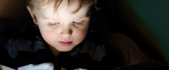 A child looking at a tablet in a dark room