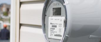 A Hydro meter on the side of a house with a worker and truck in the background.