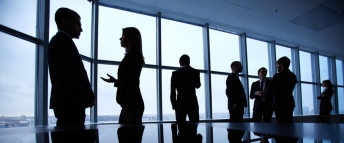 Group of colleagues standing against a window in the office and speaking