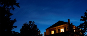 A lit house at night against a starry sky