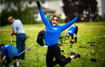 An enthusiastic volunteer jumps into the air at the tree planting event