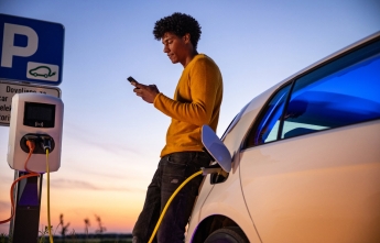 A young man browses on his phone while his vehicle charges
