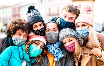 A group of young people in winter clothing and face masks pose together