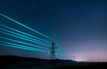 Large electrical towers with neon blue wires running across the countryside on a starry night