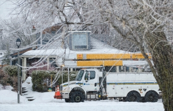 A hydro truck is parked on a snowy residential street