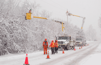 Hydro crews working in bucket trucks along a snowy road