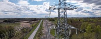 Transmission towers and distribution hydro poles run along a rural road in South-Nepean