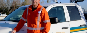 A man in a hard hat stands beside a Hydro Ottawa pick-up truck