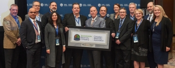 A group of Hydro Ottawa employees hold a framed plaque commemorating the company's designation as a Sustainable Electricity Company