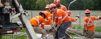 A team of hydro workers struggle to lift a downed hydro pole