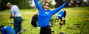 An enthusiastic volunteer jumps into the air at the tree planting event