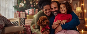 A family and their dog laugh on Christmas morning