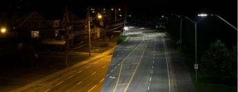 A before and after image of a street lit with old yellow-ish lighting and new brightly-lit LED lights