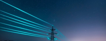 Large electrical towers with neon blue wires running across the countryside on a starry night