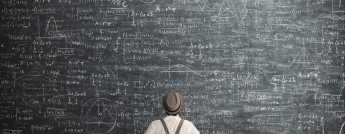 A man wearing a hat and suspenders looks at a blackboard covered in complex mathematical formulas